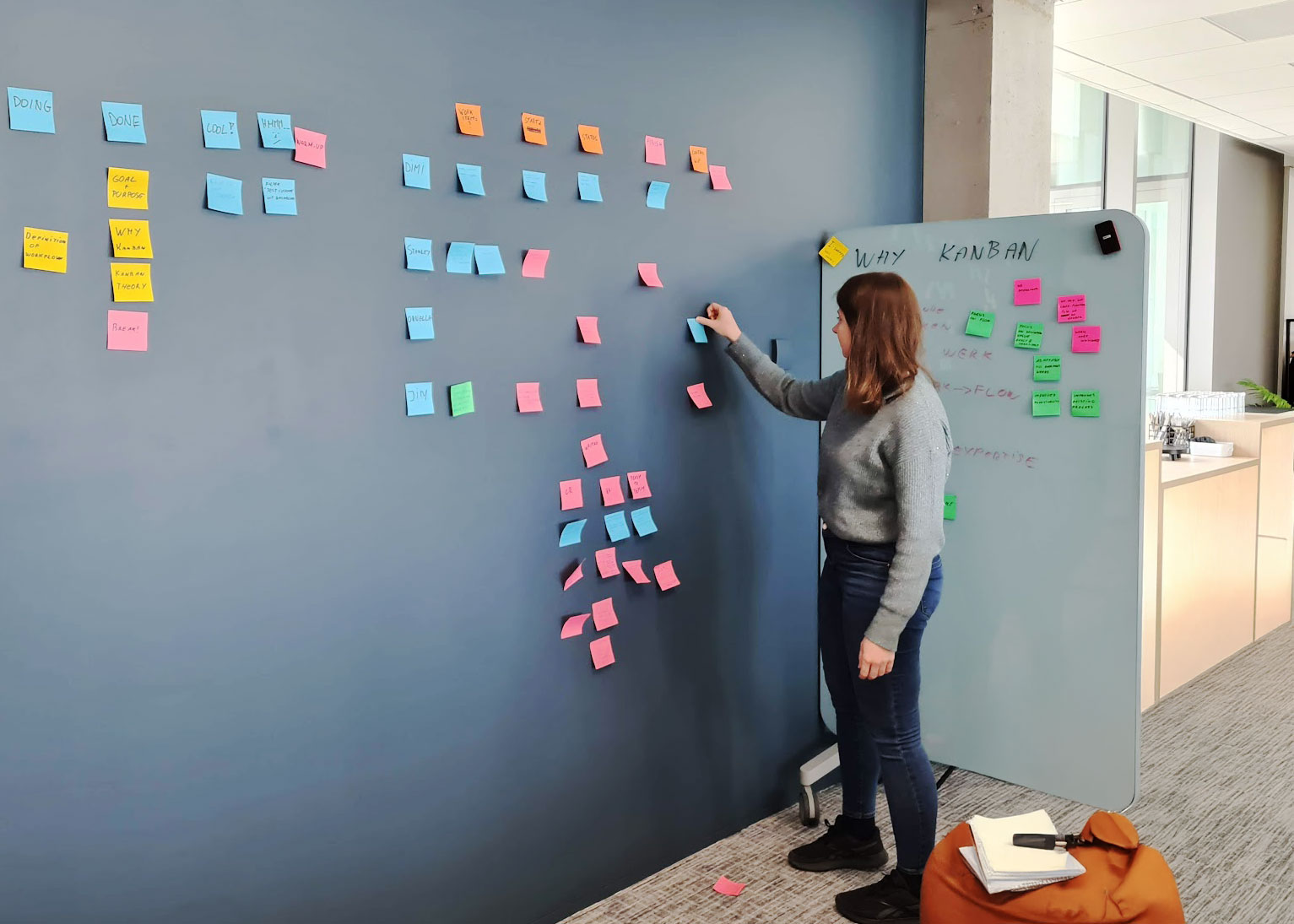 A person puts a post-it on a Kanban board.